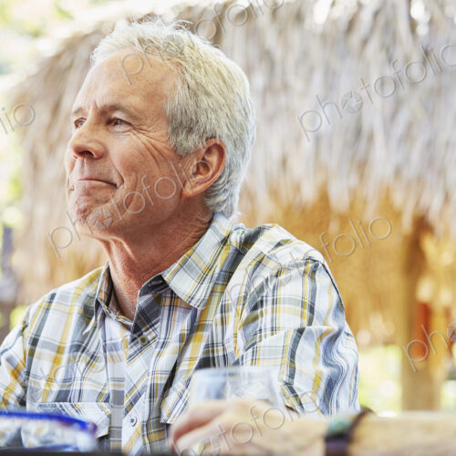 Smiling senior man with grey hair sitting outdoors.