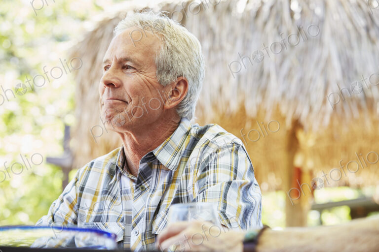 Smiling senior man with grey hair sitting outdoors.