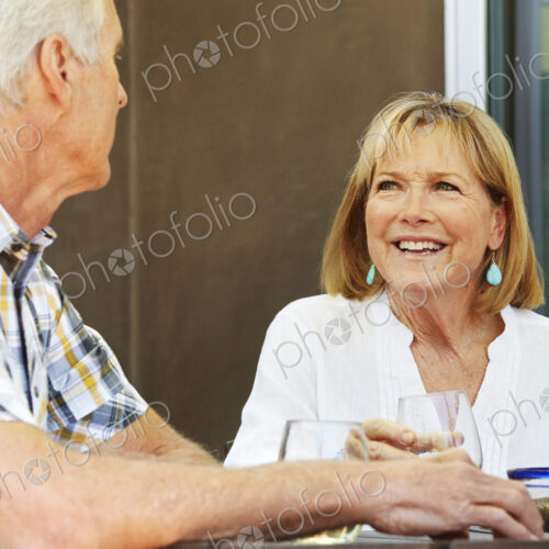 Smiling senior woman and man sitting outdoors.