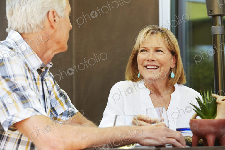 Smiling senior woman and man sitting outdoors.