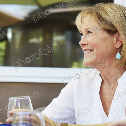 Smiling senior woman with blond hair sitting outdoors.