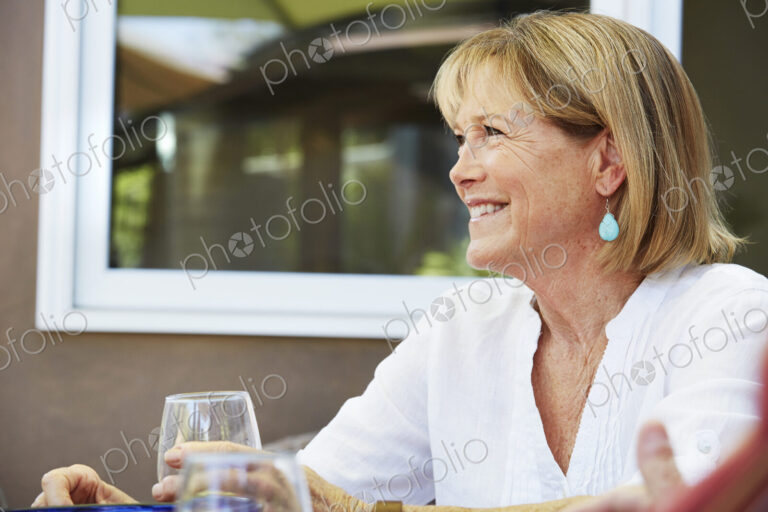 Smiling senior woman with blond hair sitting outdoors.