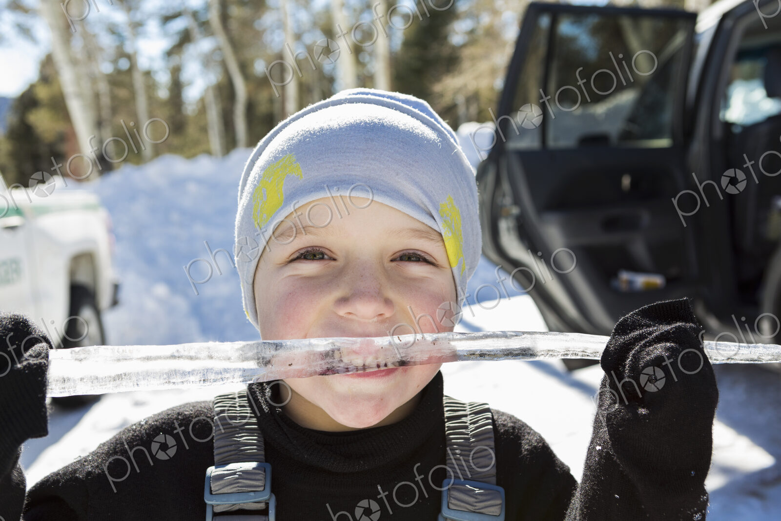 Smiling six year old boy with a long icicle in his mouth