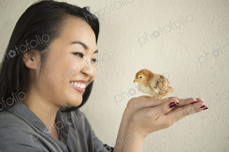Smiling woman holding a tiny chick in her hands.