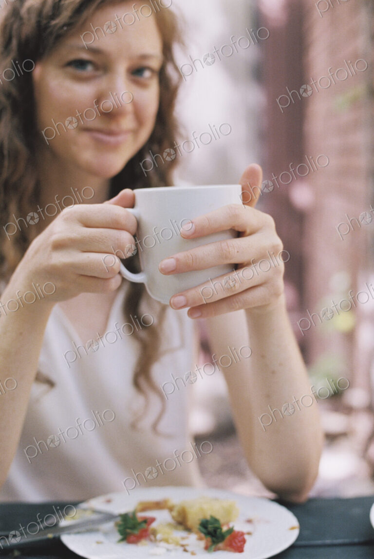 Smiling woman holding a white china teacup.