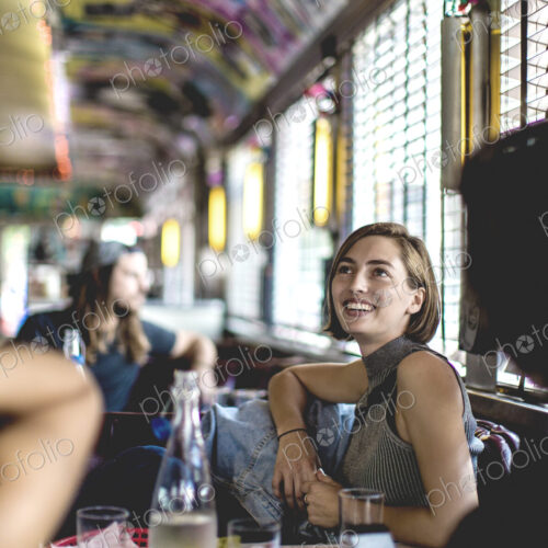 Smiling woman sitting in a booth in a diner looking up and talking to friends. Smiling woman sitting in a booth in a diner looking up and talking to friends.
