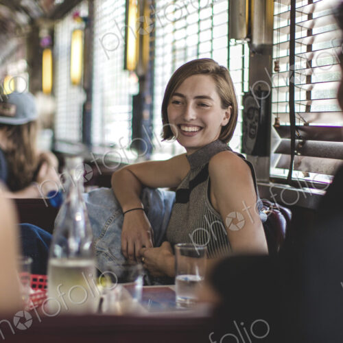 Smiling woman sitting with two friends in a booth in a diner. Smiling woman sitting with two friends in a booth in a diner.