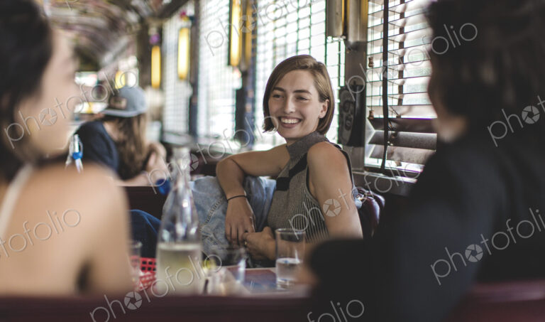 Smiling woman sitting with two friends in a booth in a diner.
