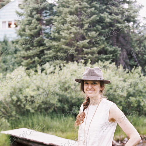 Smiling woman standing by a wooden bridge over a stream. Smiling woman standing by a wooden bridge over a stream.