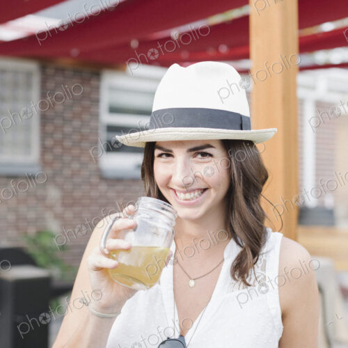 Smiling woman standing in a garden, holding a drink. Smiling woman standing in a garden, holding a drink.
