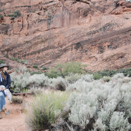 Smiling woman with auburn hair, wearing a hat sitting on a bench in a canyon. Smiling woman with auburn hair, wearing a hat sitting on a bench in a canyon.