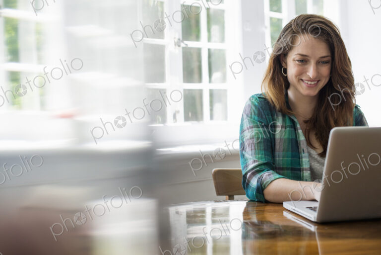 Smiling woman with laptop in home office.