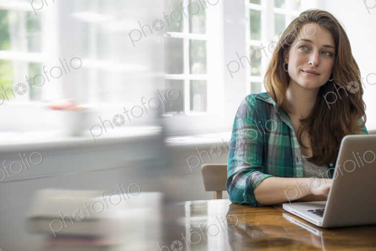 Smiling woman with laptop in home office.