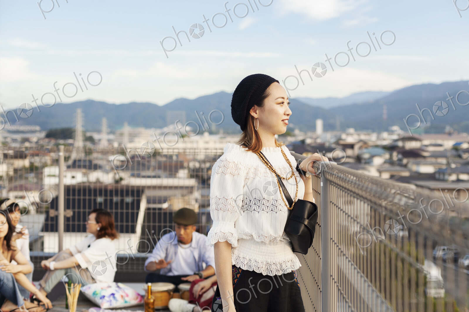 Smiling young Japanese woman standing on a rooftop in an urban setting.