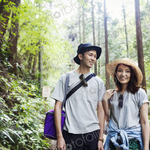 Smiling young woman and man standing in a forest.