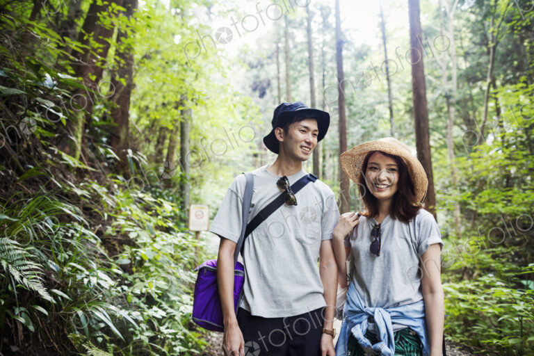 Smiling young woman and man standing in a forest.