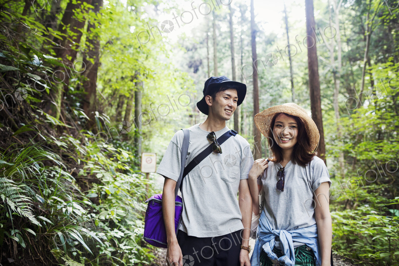 Smiling young woman and man standing in a forest.