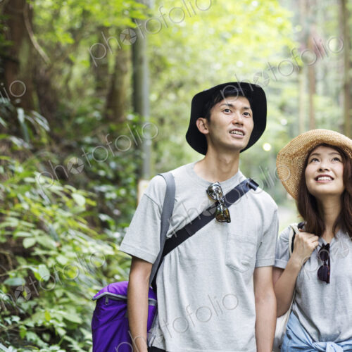Smiling young woman and man standing in a forest.