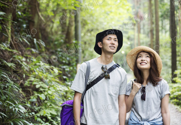 Smiling young woman and man standing in a forest.