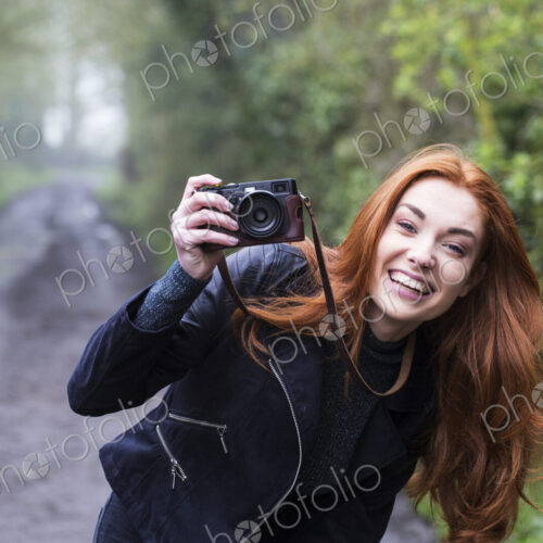 Smiling young woman outdoors taking pictures with vintage camera. Smiling young woman outdoors taking pictures with vintage camera.