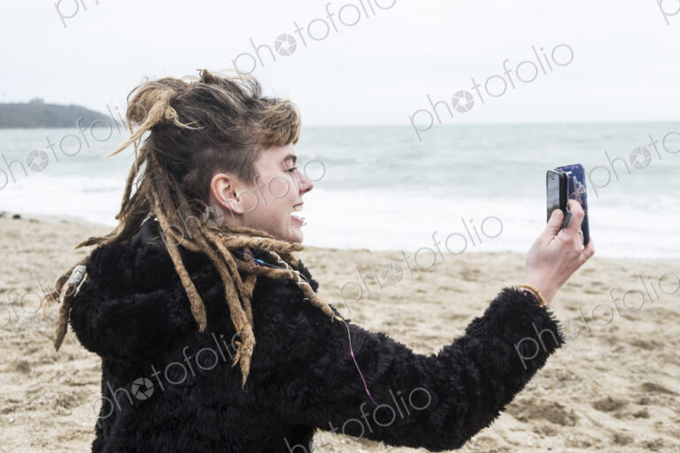 Smiling young woman with brown hair and dreadlocks and a lip piercing wearing black…