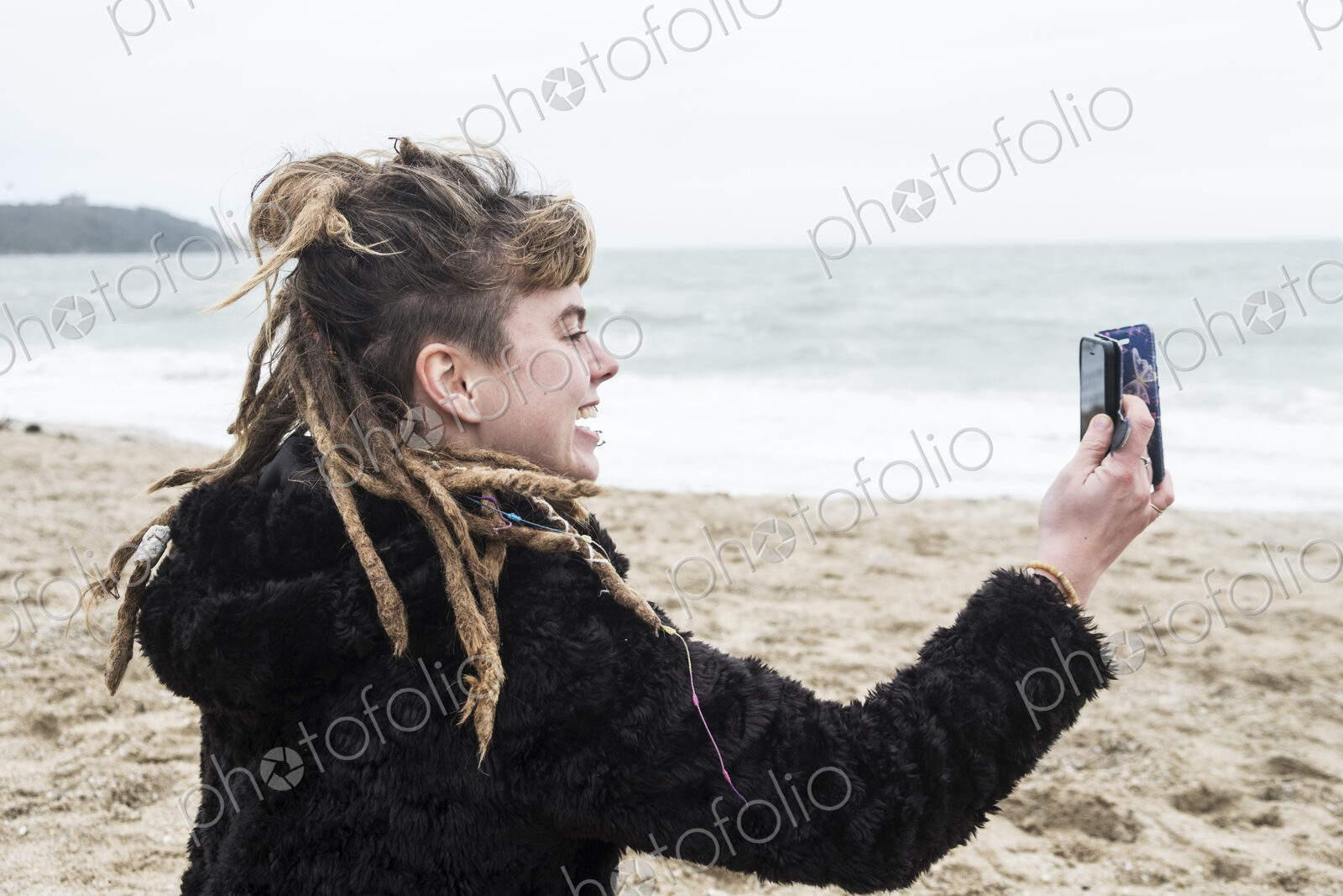 Smiling young woman with brown hair and dreadlocks and a lip piercing wearing black…