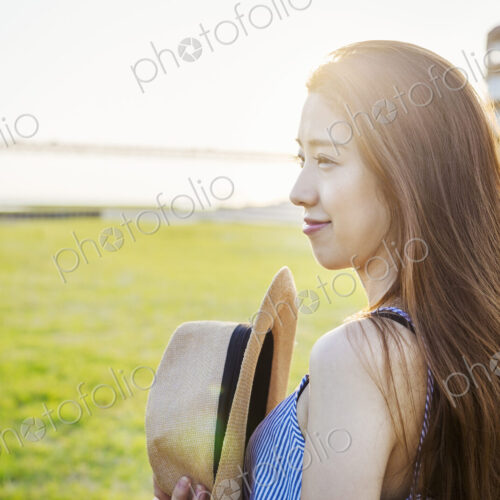 Smiling young woman with long brown hair, holding Panama hat.