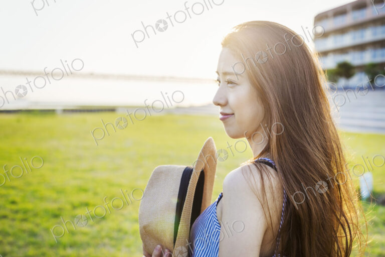 Smiling young woman with long brown hair, holding Panama hat.