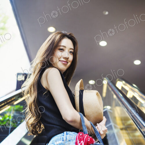 Smiling young woman with long brown hair on an escalator. Smiling young woman with long brown hair on an escalator.