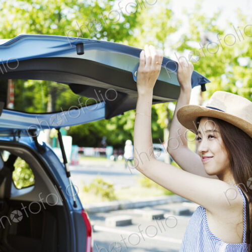 Smiling young woman with long brown hair, wearing Panama hat, closing the rear hatch… Smiling young woman with long brown hair, wearing Panama hat, closing the rear hatch…