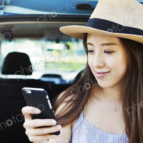 Smiling young woman with long brown hair, wearing Panama hat, using a mobile phone. Smiling young woman with long brown hair, wearing Panama hat, using a mobile phone.