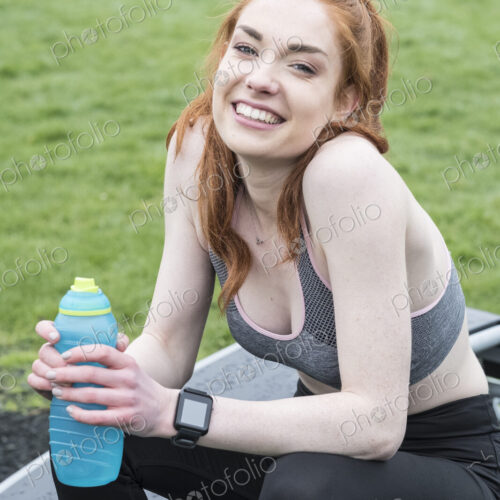 Smiling young woman with long red hair wearing sportswear, exercising outdoors,… Smiling young woman with long red hair wearing sportswear, exercising outdoors,…