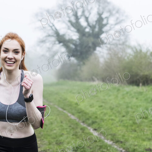 Smiling young woman with long red hair wearing sportswear, exercising outdoors,… Smiling young woman with long red hair wearing sportswear, exercising outdoors,…