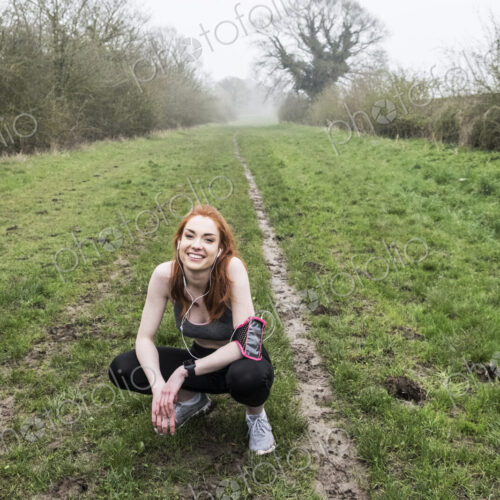 Smiling young woman with long red hair wearing sportswear, exercising outdoors,… Smiling young woman with long red hair wearing sportswear, exercising outdoors,…