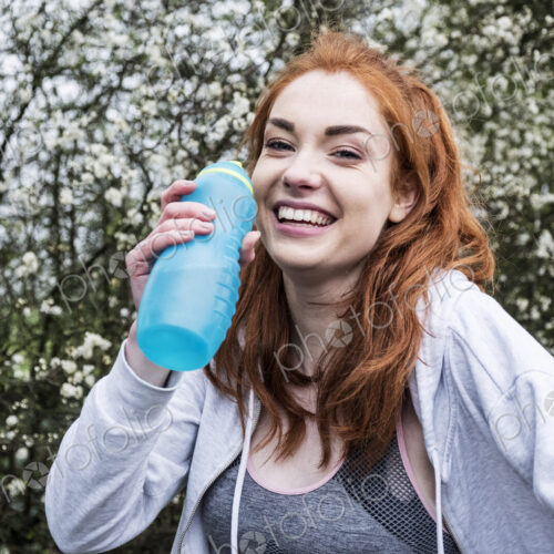 Smiling young woman with long red hair wearing sportswear, exercising outdoors,… Smiling young woman with long red hair wearing sportswear, exercising outdoors,…