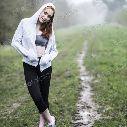 Smiling young woman with long red hair wearing sportswear, exercising outdoors,… Smiling young woman with long red hair wearing sportswear, exercising outdoors,…