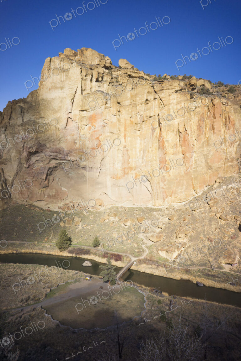 Smith Rocks cliff face in pale sandstone above the water of the Crooked River in Oregon.