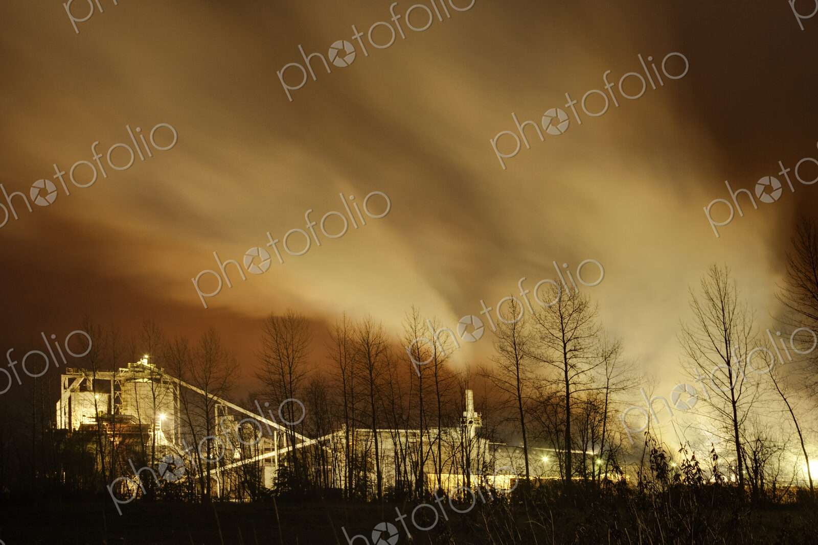 Smoke stacks of a factory at sunset, smoke billowing out at sunset.