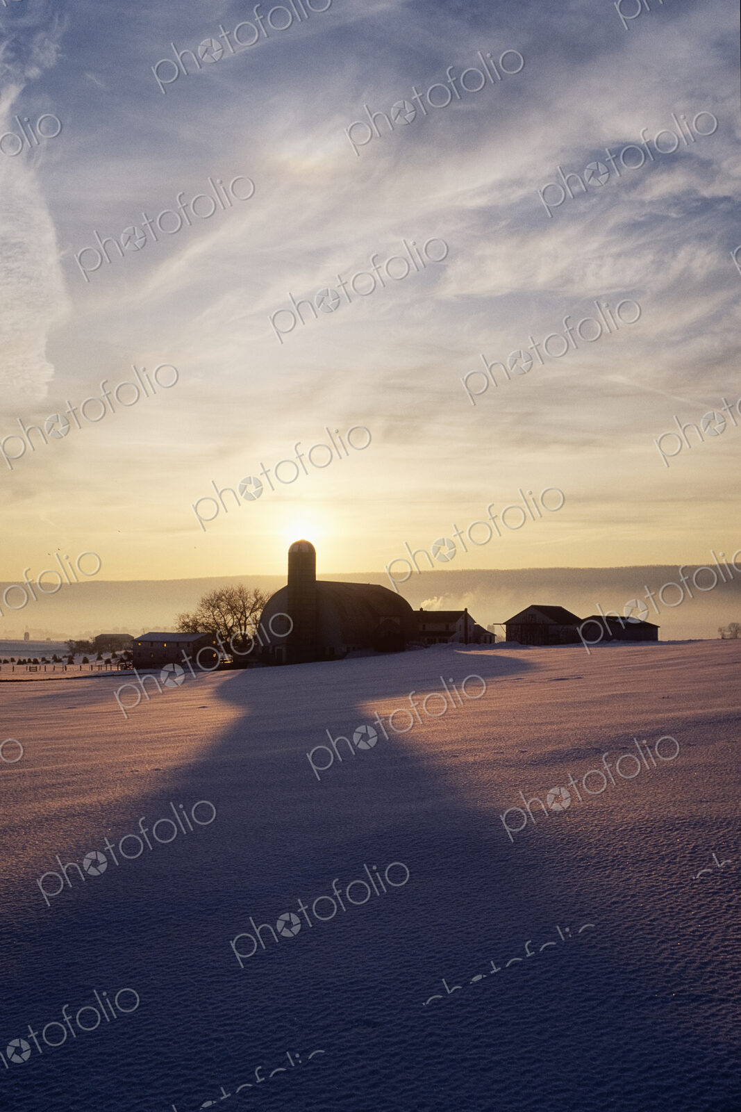 Snow Covered Field with Farm Silhouette at Sunset