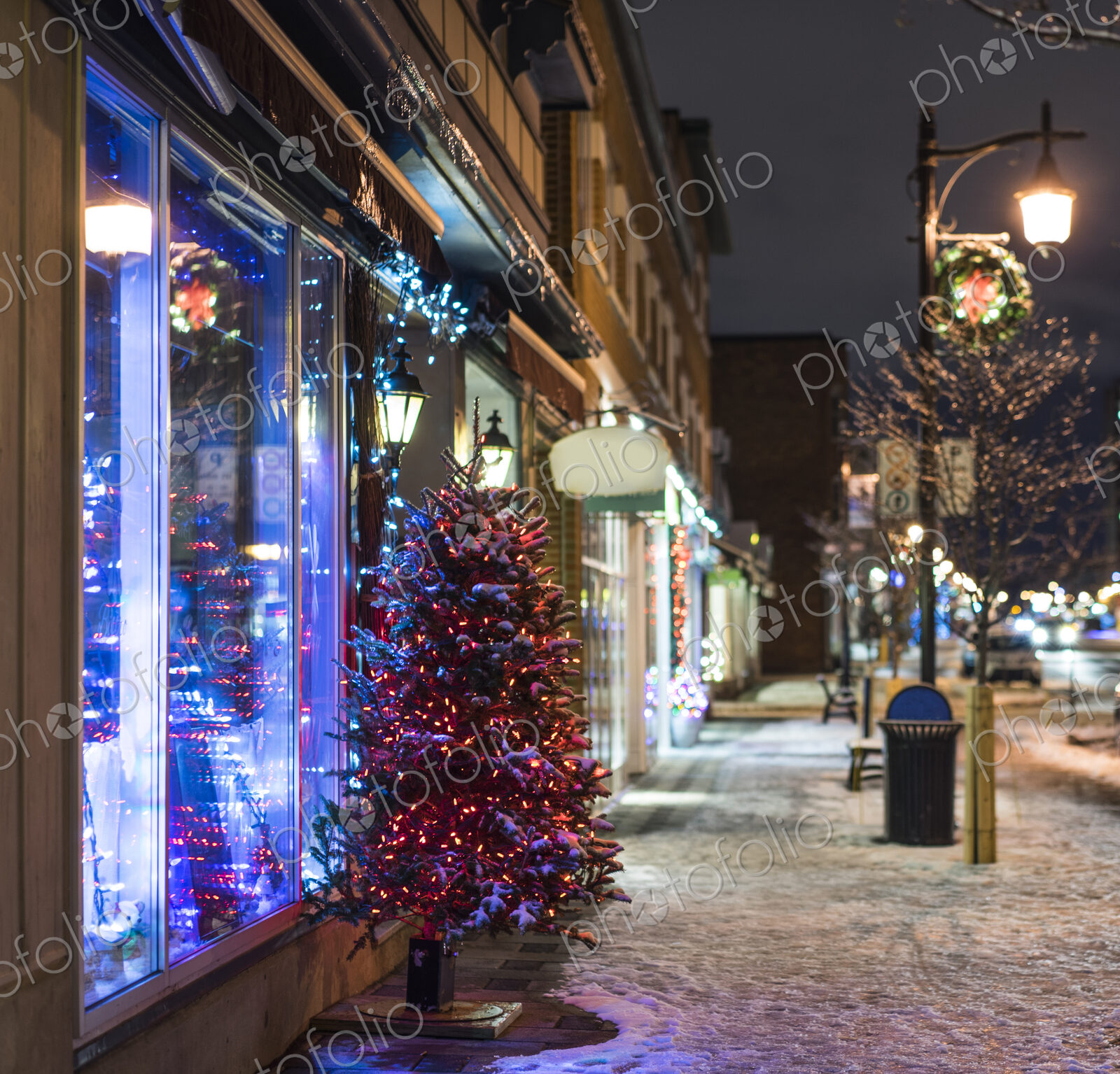 Snow and Christmas tree on city sidewalk at night