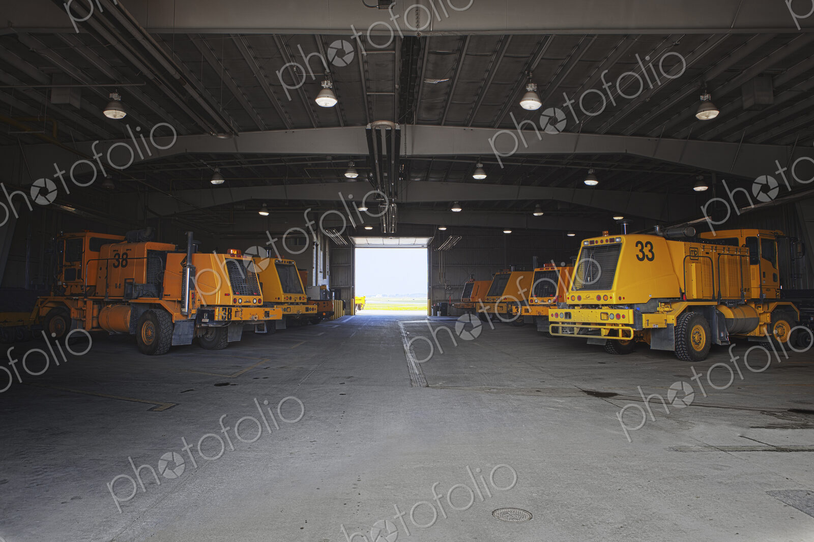 Snow ploughs and maintenance vehicles in a garage at an airport.
