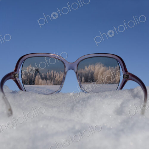 Snowy winter landscape view through sunglasses. Reflection.