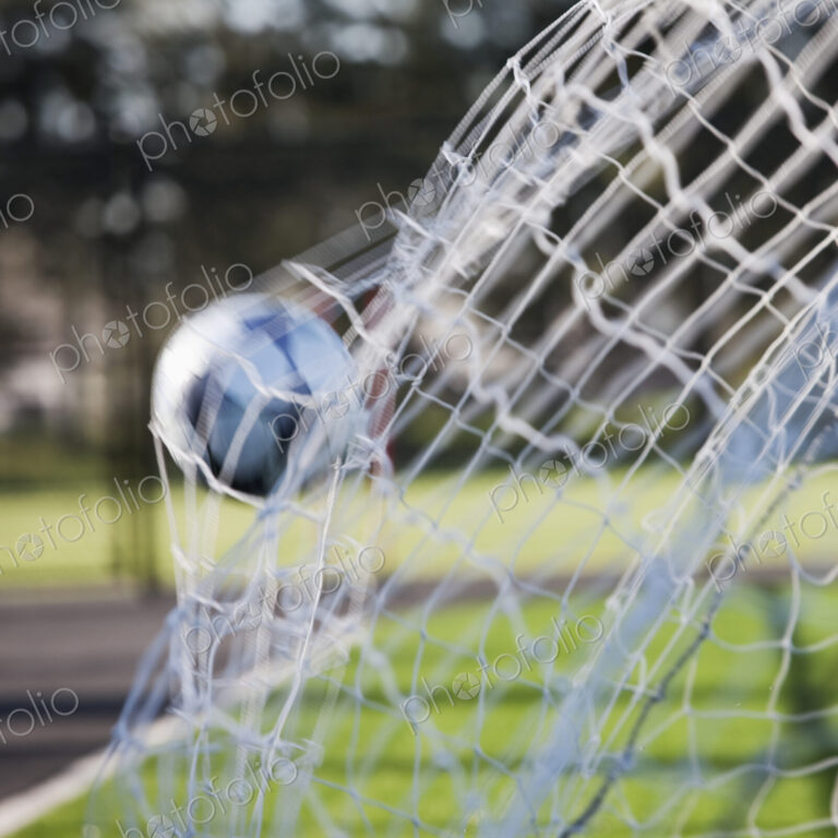 Soccer ball hitting the back of a football net.