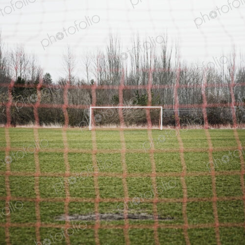 Soccer field seen through soccer goal net.