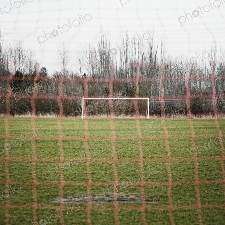 Soccer field seen through soccer goal net.