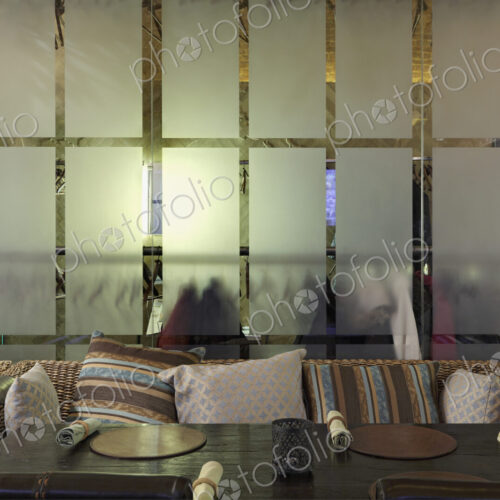 Sofa with many pillows against glass wall in restaurant. Sofa with many pillows against glass wall in restaurant.