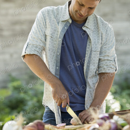 Sorting and chopping freshly picked vegetables and fruits. A man using a sharp knife.
