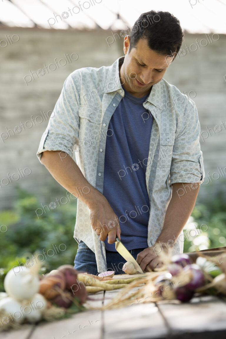 Sorting and chopping freshly picked vegetables and fruits. A man using a sharp knife.