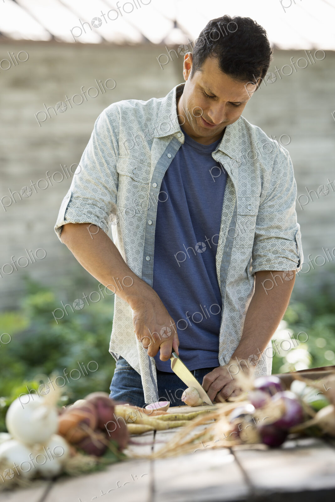 Sorting and chopping freshly picked vegetables and fruits. A man using a sharp knife.
