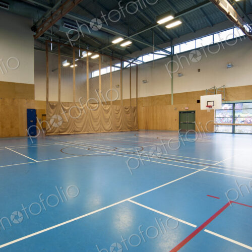 Spacious gymnasium with a basketball court floor markings, light and airy, glass doors